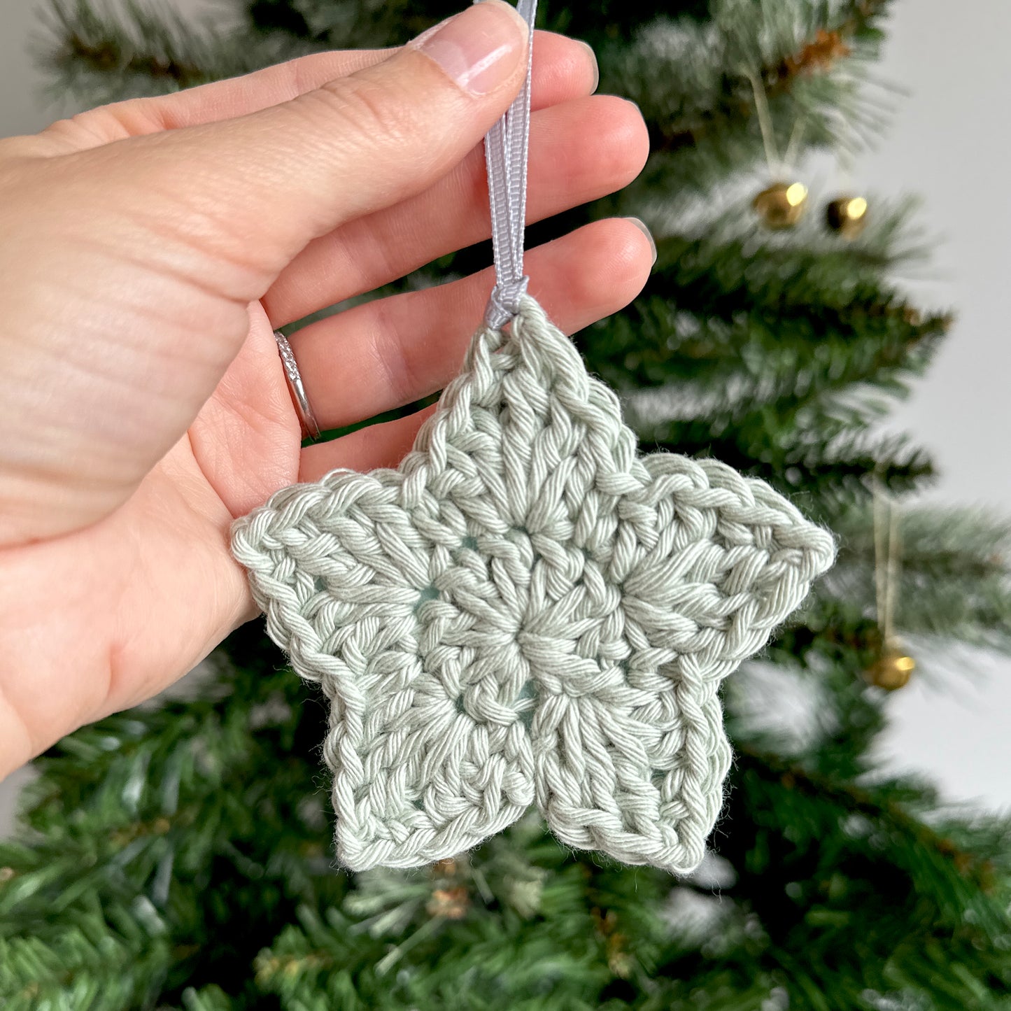 Pale green crochet star decoration in front of Christmas tree