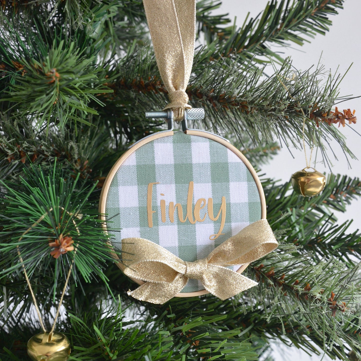 Personalised Christmas ornament with green check design and gold ribbon hanging on a tree.