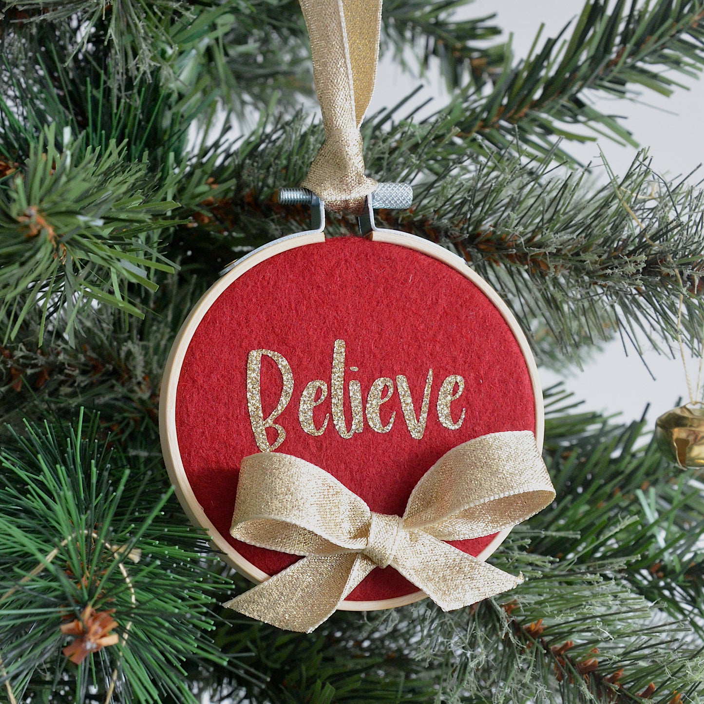 Red decorative hoop hanging on Christmas tree with the text "believe".