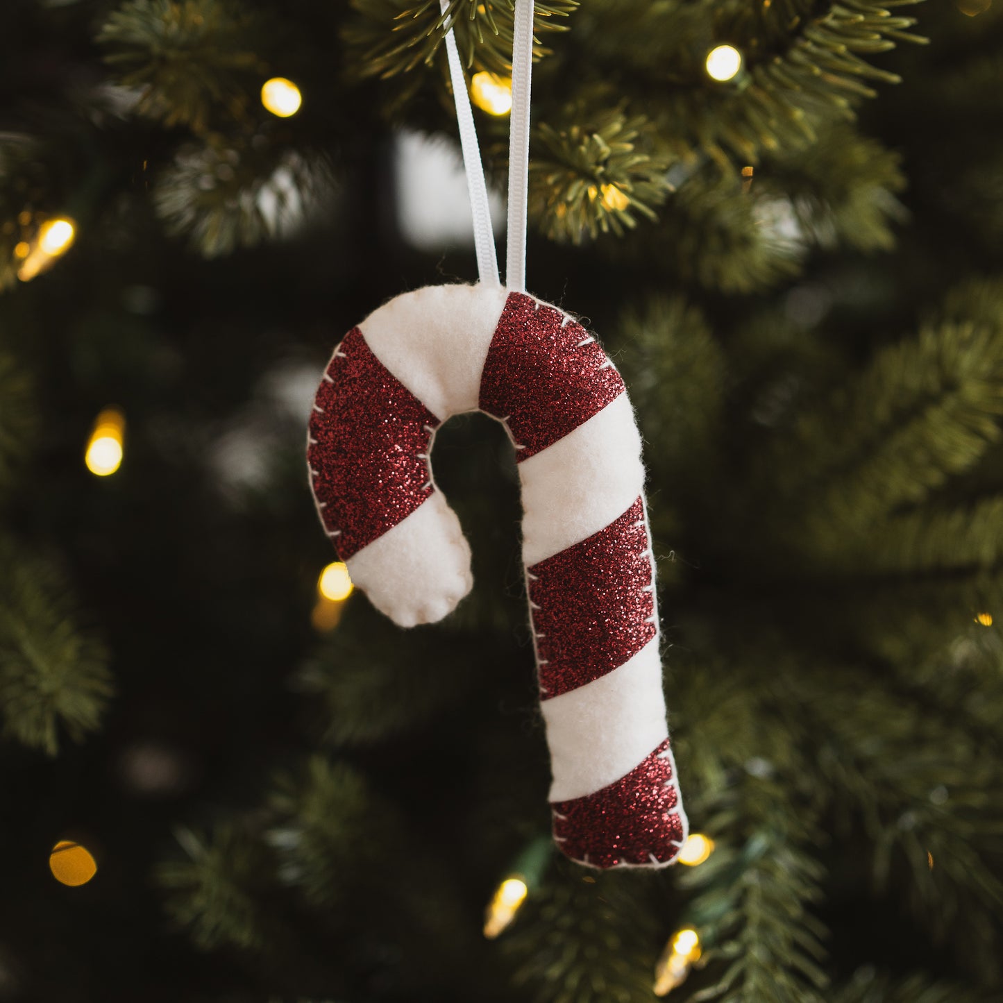 Red candy cane decoration hanging on a Christmas tree