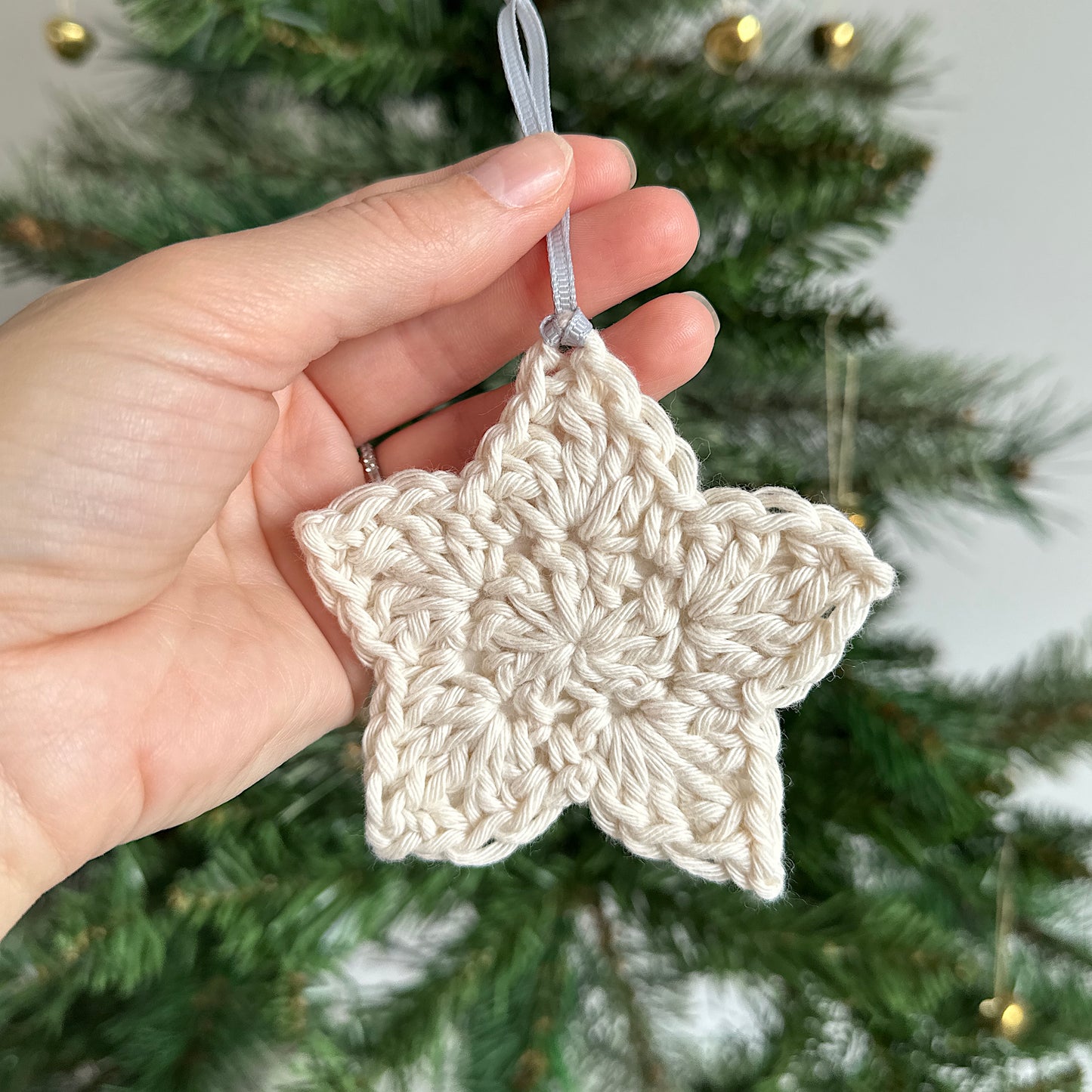 A cream star decoration in front of a Christmas tree
