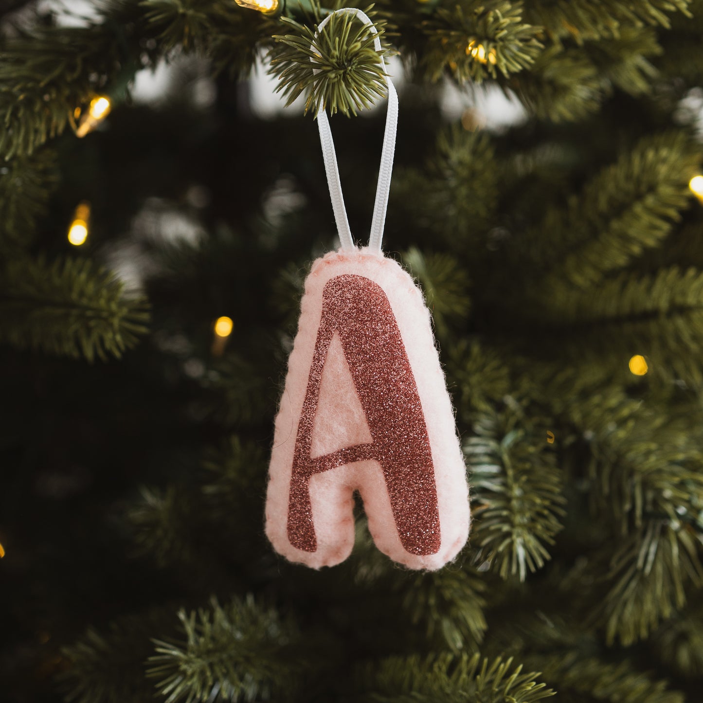 Pink initial decoration hanging on a Christmas tree