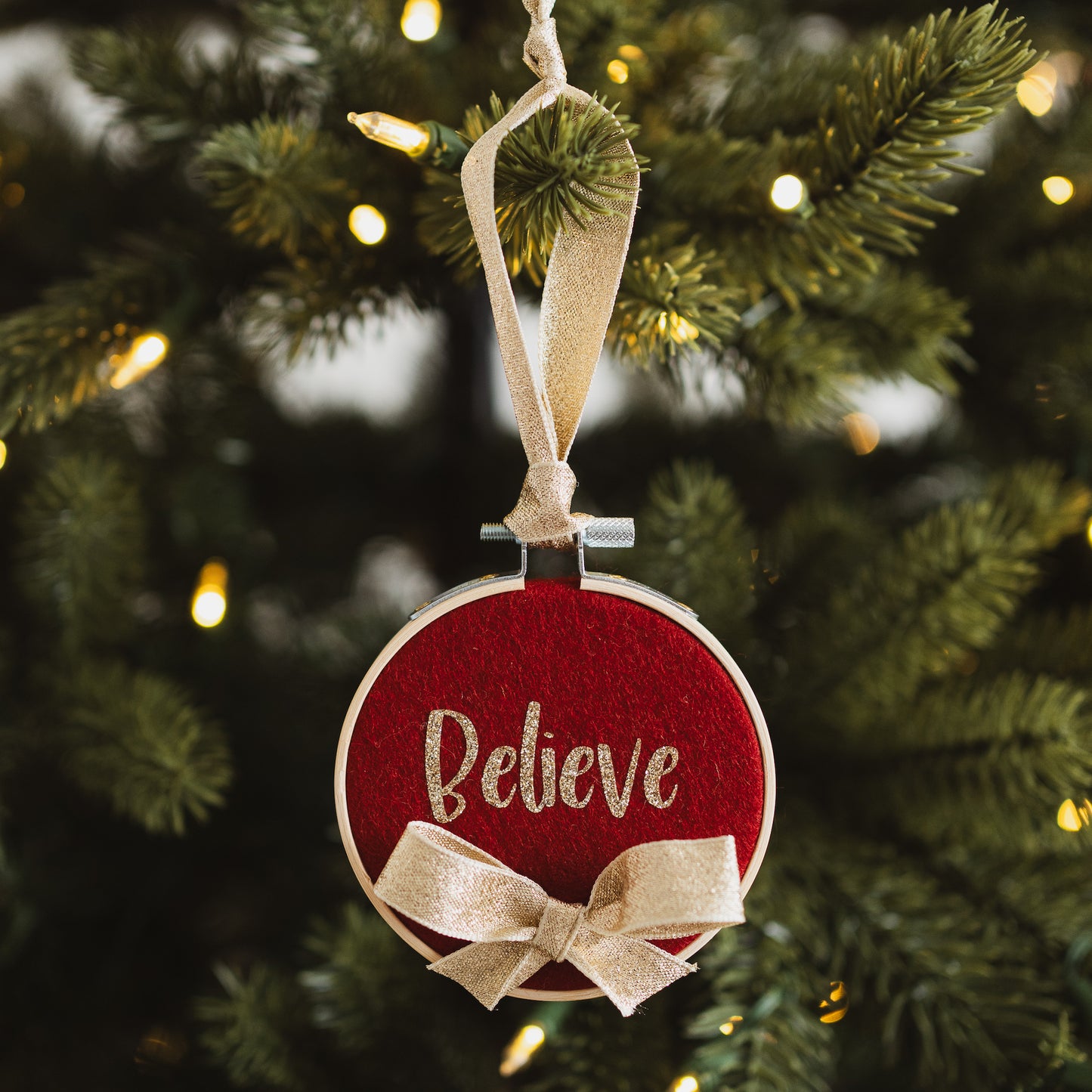 Red decorative hoop hanging on Christmas tree with the text "believe".