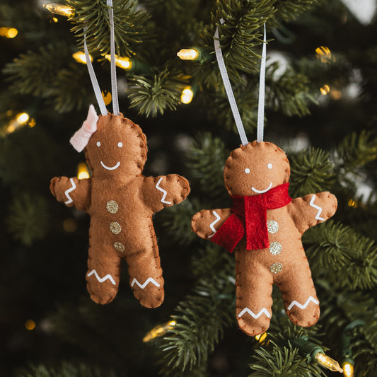 Two gingerbread man decorations hanging on a Christmas tree.
