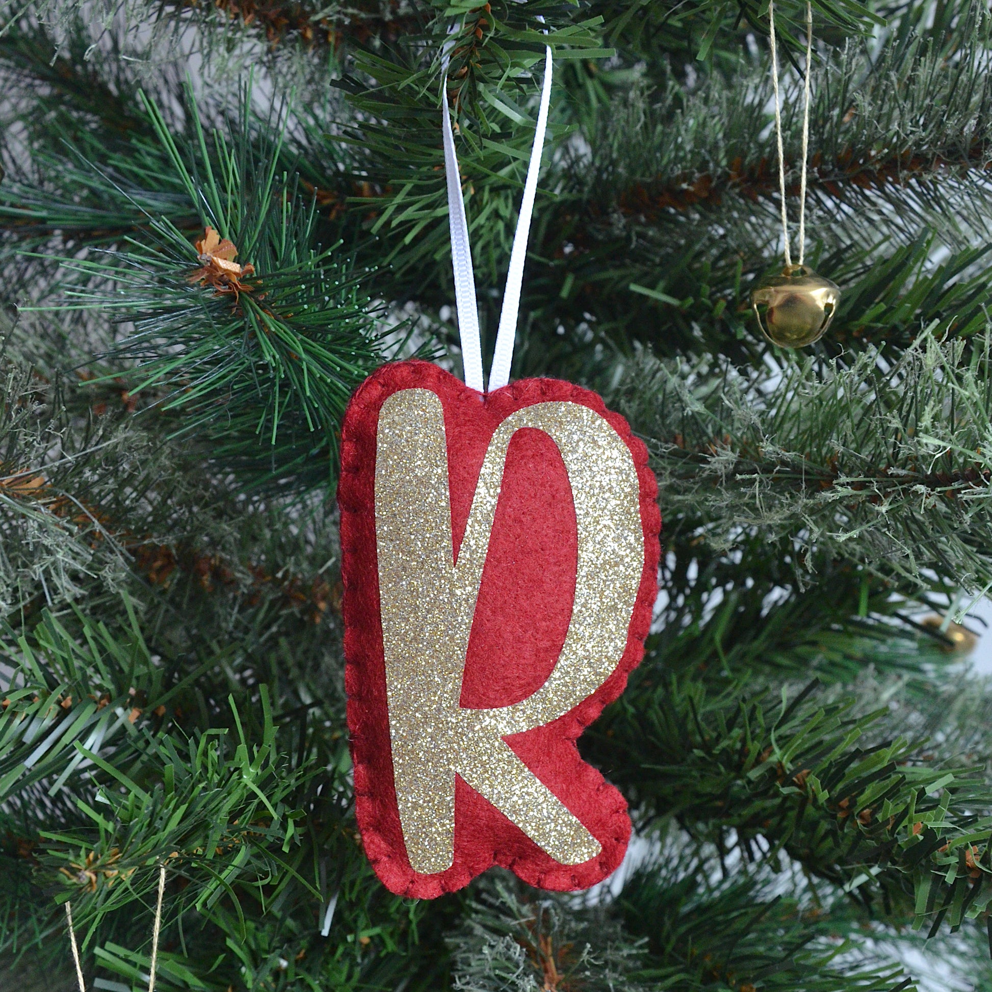 Personalised red and gold letter decoration on a Christmas tree