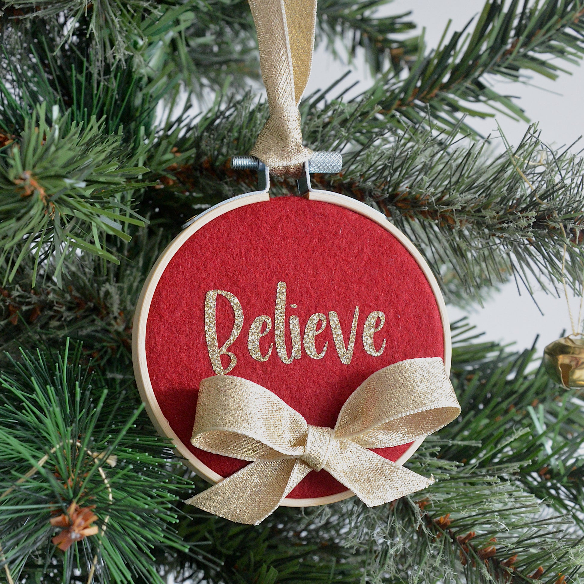 Red decorative hoop hanging on Christmas tree with the text "believe".