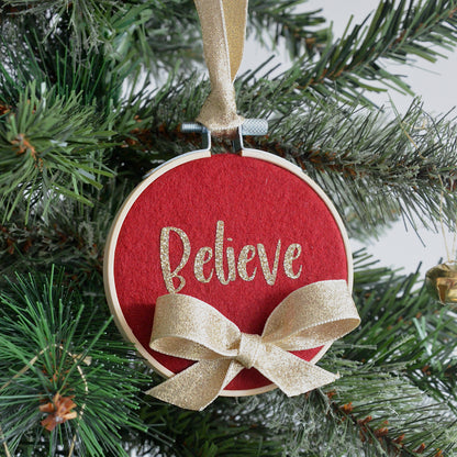 Red decorative hoop hanging on Christmas tree with the text "believe".