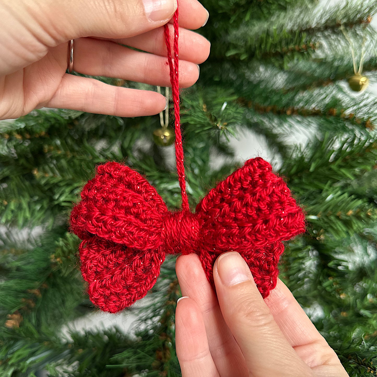 Red crocheted bow decoration in front of a Christmas tree