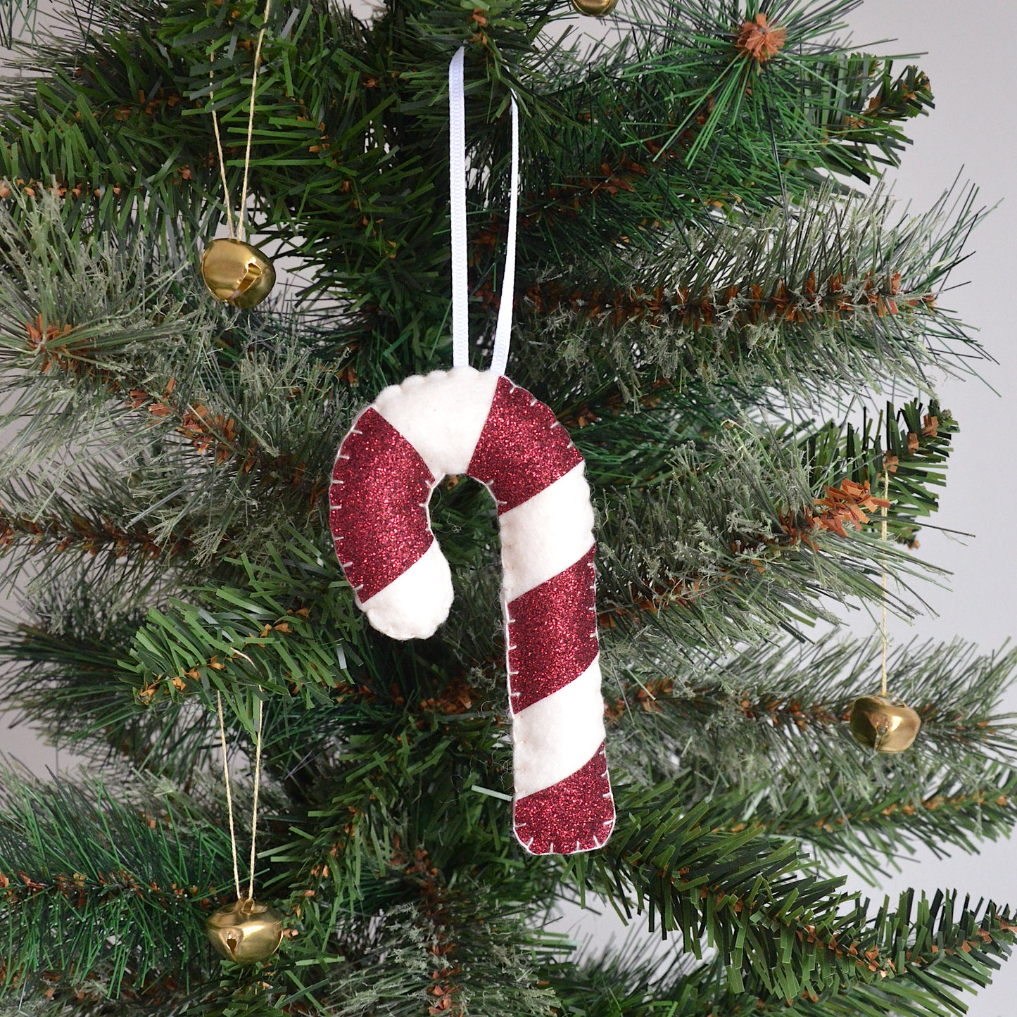 Red candy cane decoration hanging on a Christmas tree