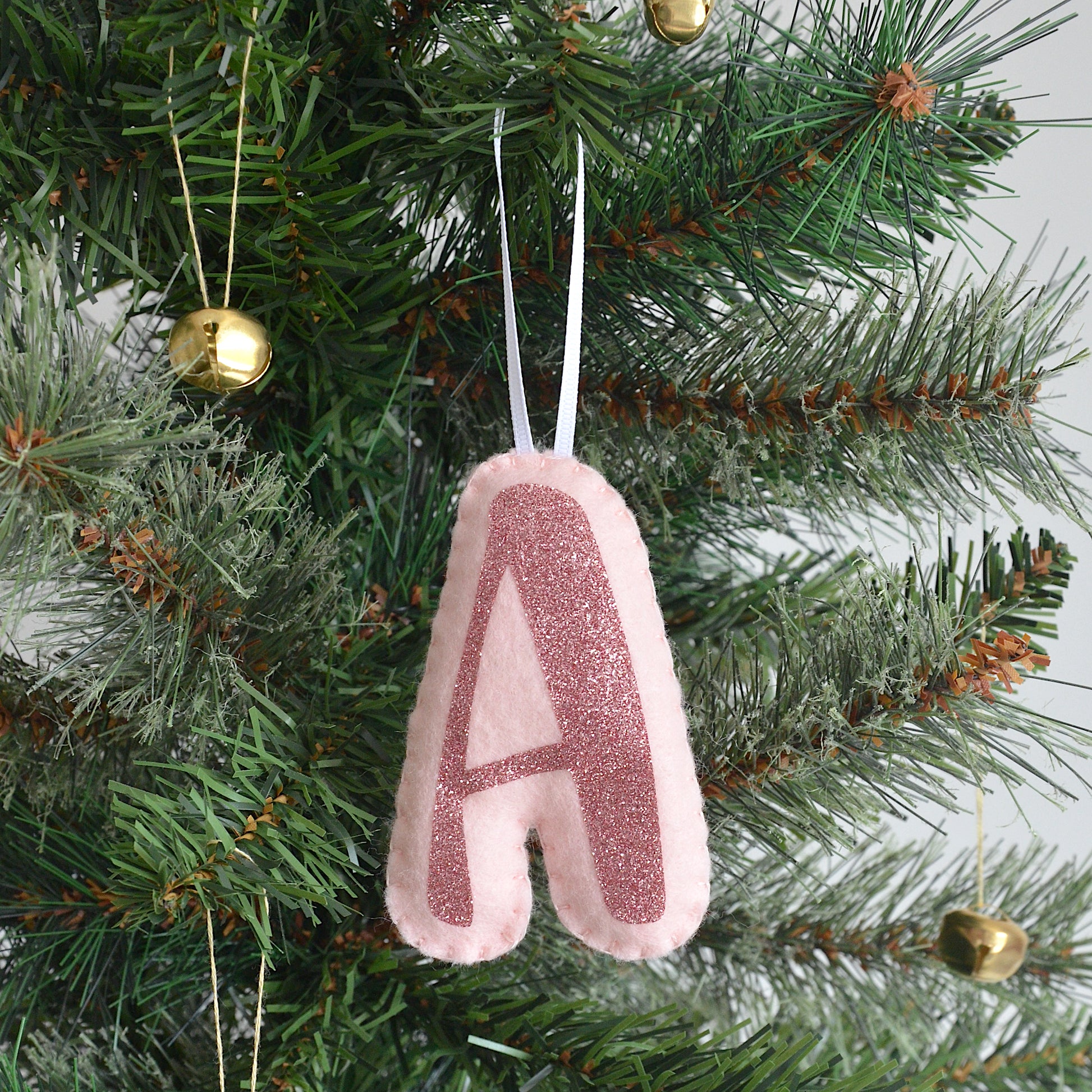 Pink initial decoration hanging on a Christmas tree
