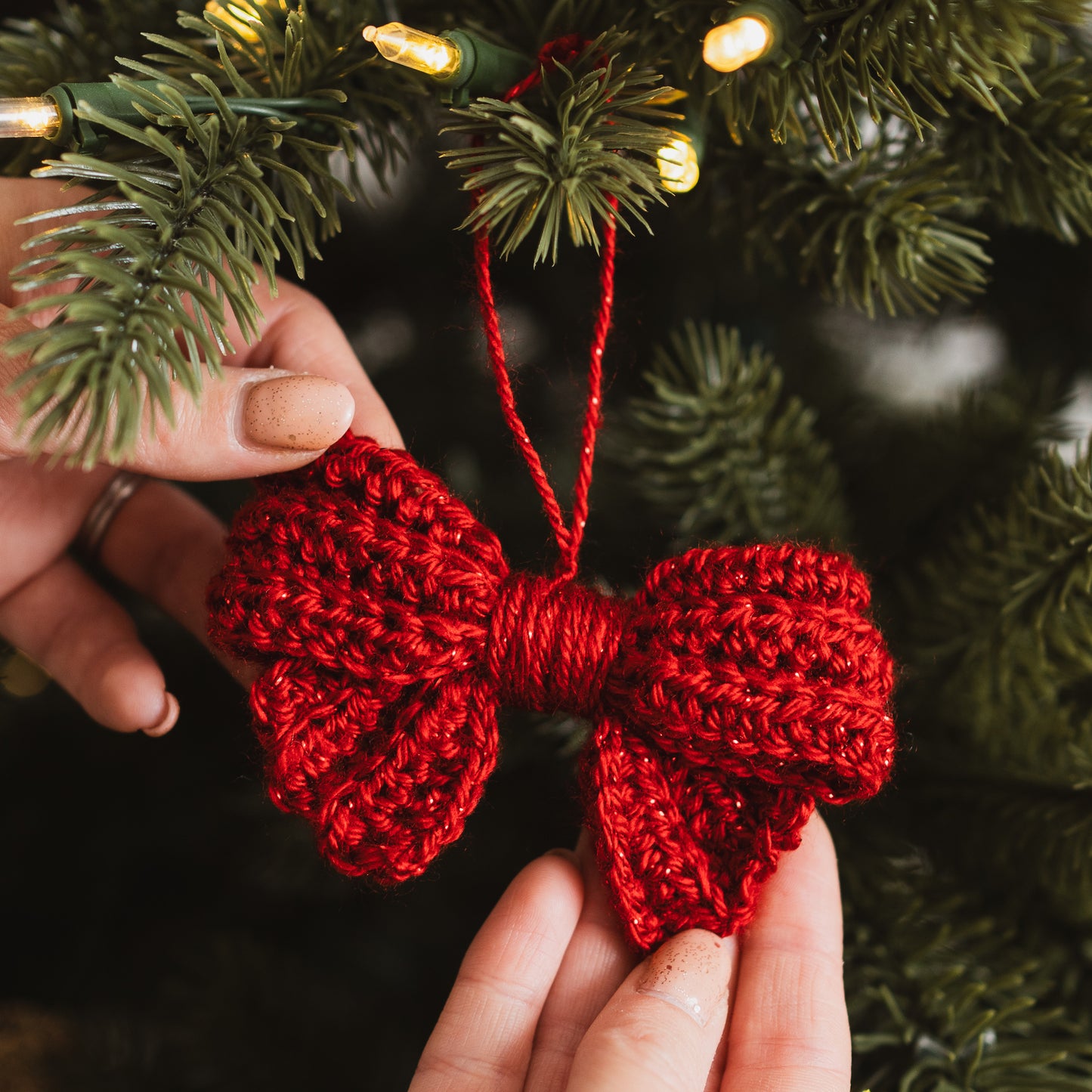 Red crocheted bow decoration in front of a Christmas tree